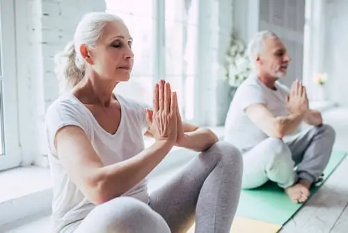 White elderly couple doing yoga 