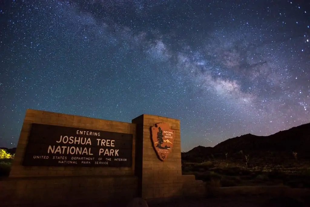 Night sky and Milky Way shown above Joshua Tree National Park entrance sign