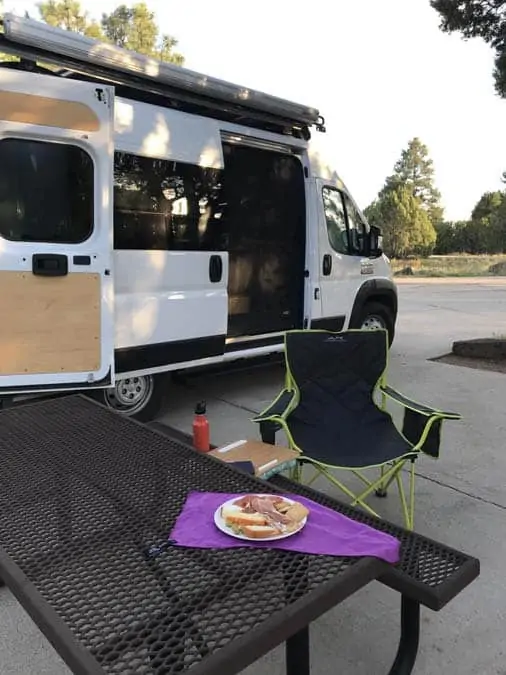 Women camping alone in Fool Hollow Campground.  Show Low, AZ.  Spanish tapas dinner with a view.  converted Promaster van in background.